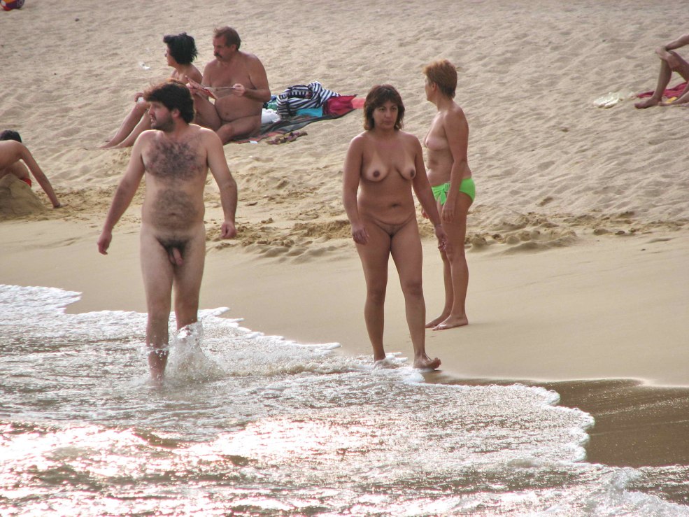 Les gars nus sur la plage parmi des